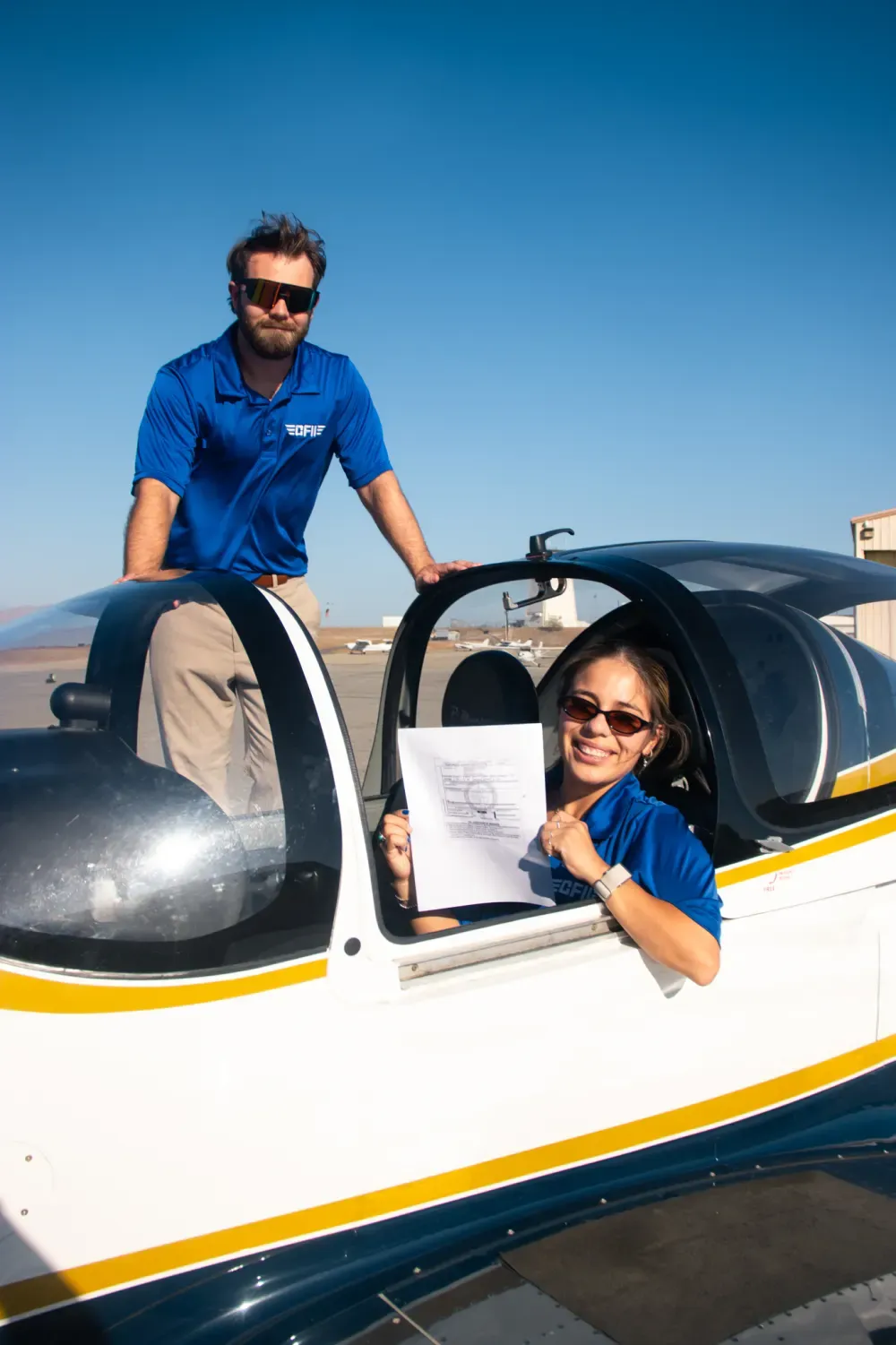 A student in the cockpit holding a new temporary airman certificate