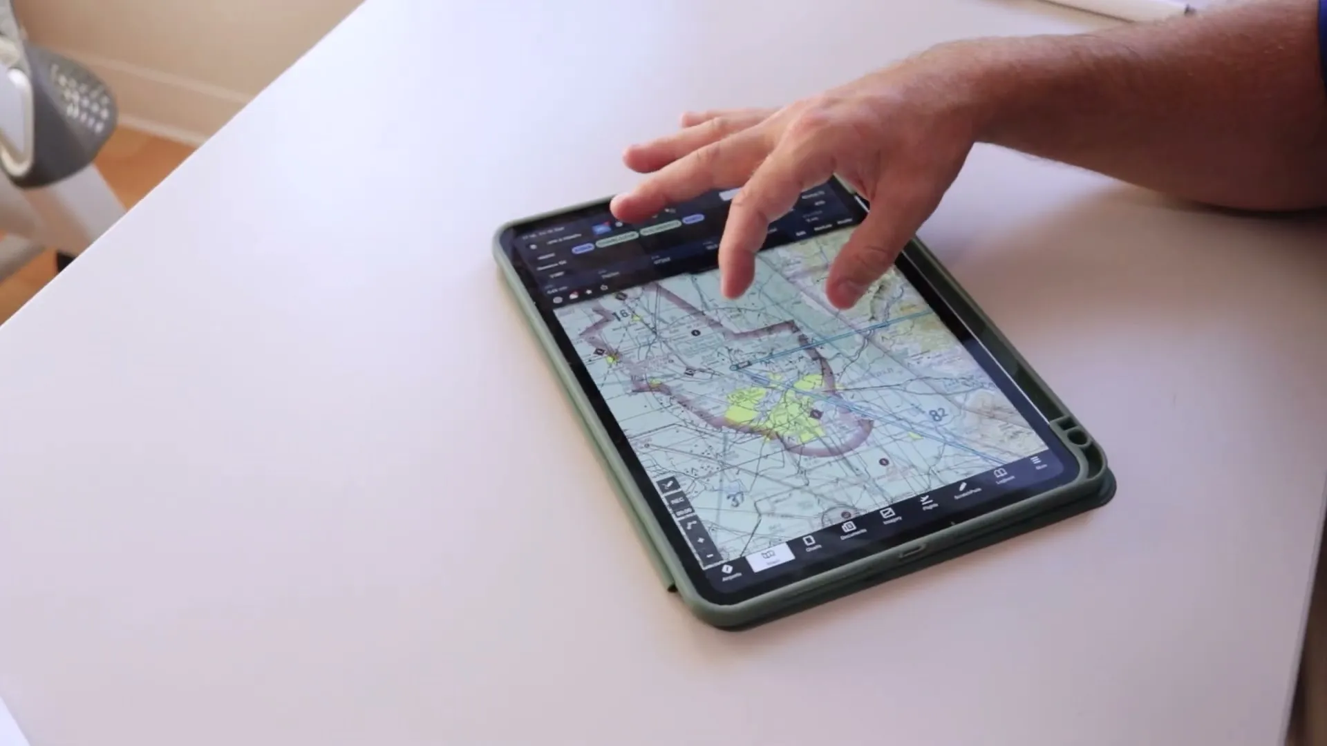 A hand on a tablet showing an aviation chart