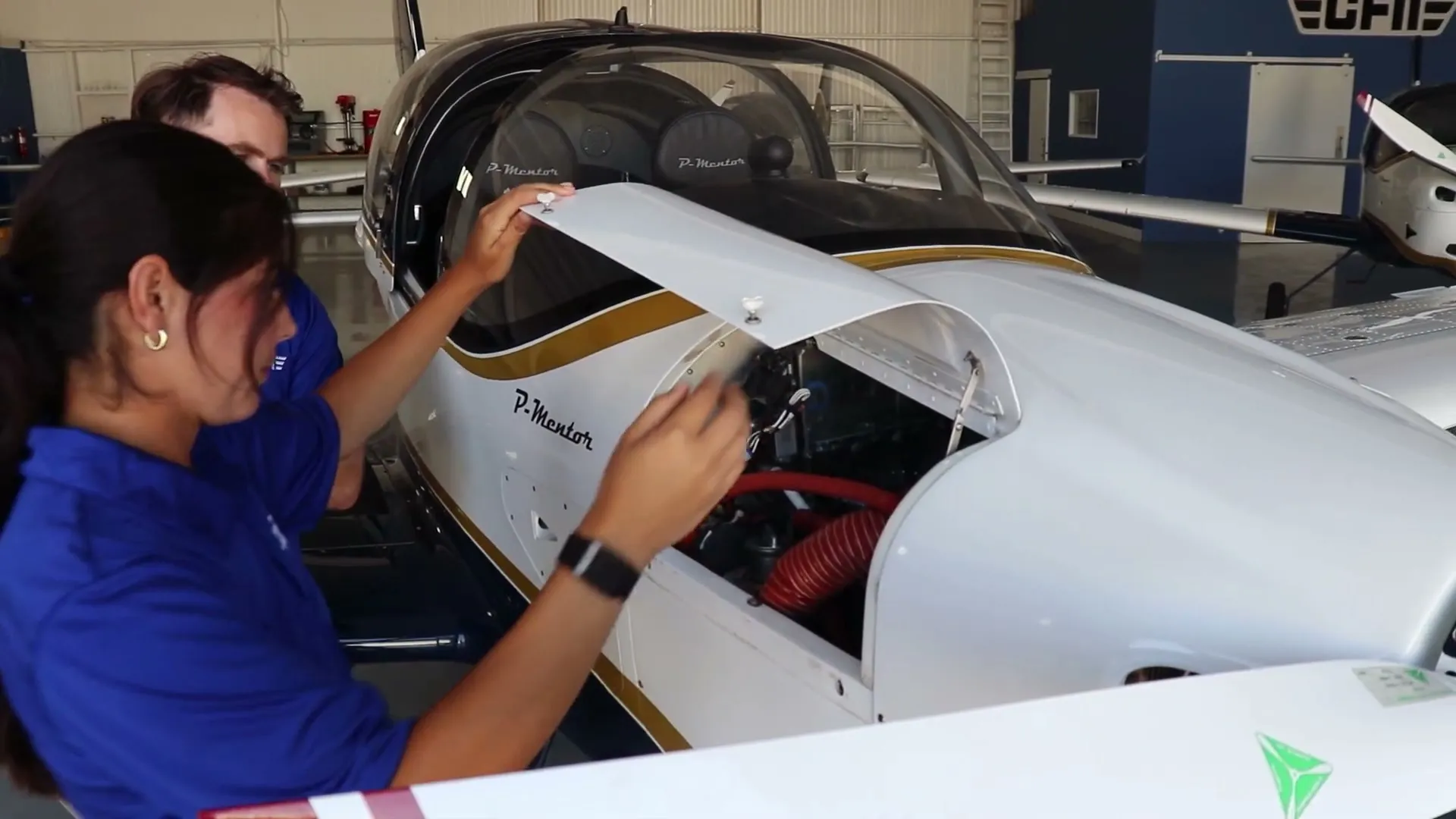 A student and an instructor checking the engine of a P-Mentor before a flight