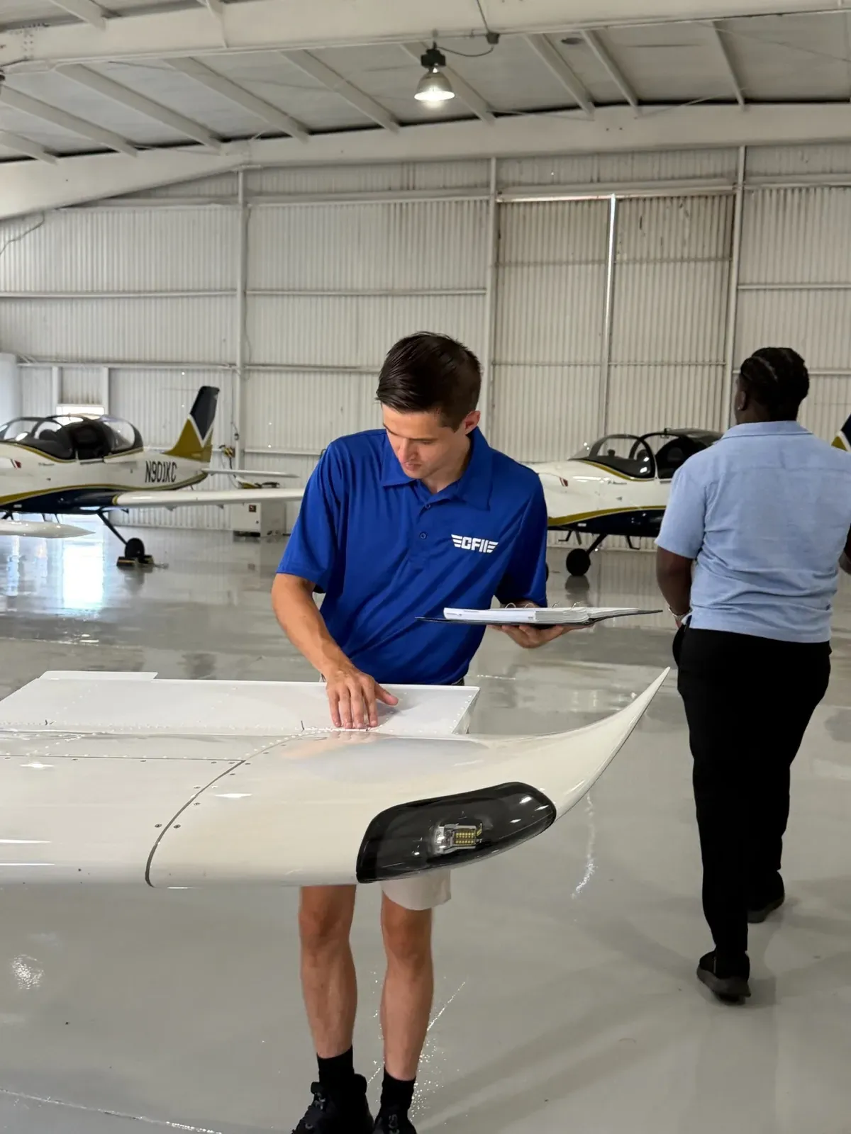 CFII instructor walking the wing of a P-Mentor in the hangar